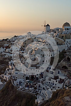 Sunset over white windmills in town of Oia and panorama to Santorini island, Thira, Greece