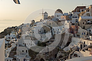 Sunset over white windmills in town of Oia and panorama to Santorini island, Thira, Greece