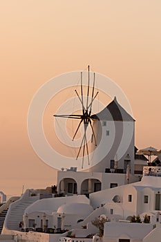 Sunset over white windmills in town of Oia and panorama to Santorini island, Thira, Greece