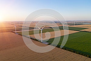 Sunset over the windmills. Wind turbines over fields of wheat and sunflowers