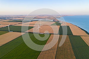 Sunset over the windmills. Wind turbines over fields of wheat and sunflowers