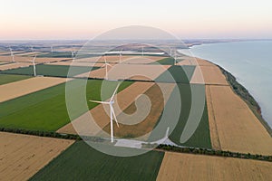 Sunset over the windmills. Wind turbines over fields of wheat and sunflowers