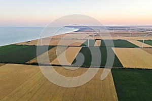 Sunset over the windmills. Wind turbines over fields of wheat and sunflowers