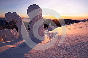 Sunset over the winter landscape from the top of a snowy hill.