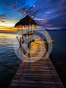 Sunset over wooden beach bar in sea and hut on pier in koh Mak island, Trat, Thailand