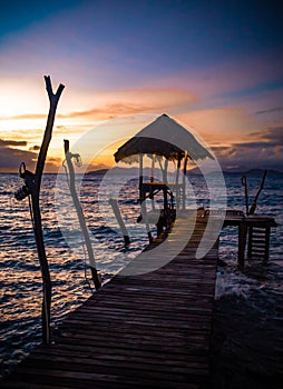 Sunset over wooden beach bar in sea and hut on pier in koh Mak island, Trat, Thailand