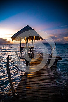 Sunset over wooden beach bar in sea and hut on pier in koh Mak island, Trat, Thailand