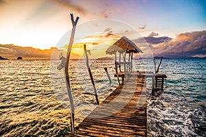 Sunset over wooden beach bar in sea and hut on pier in koh Mak island, Trat, Thailand