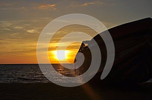 sunset over wooden boat on a beach