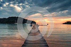 Sunset over wooden pier and boat in tropical sea at Koh Kood Island