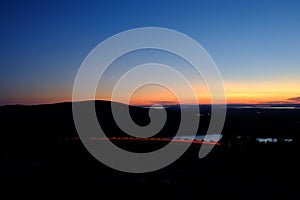 Sunset overlooking Cadillac Mountain in Maine with traffic streaking past