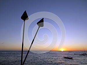 Sunset on Pacific Ocean with tiki torches and canoes