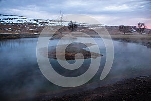 Sunset panorama of boiling steaming hot warm spring thermal lake pond in Reykholt Borgarfjordur Western Iceland