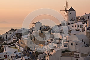 Sunset panorama over white windmills in town of Oia and panorama to Santorini island, Thira, Greece