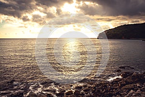 Sunset pebbles beach with dramatic golden sky and water surface on coastline