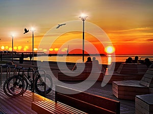 Sunset at pier city promenade people walk  Silhouette  and sit on wooden veranda seaside enjoy  sundown at orange sea landscape bi