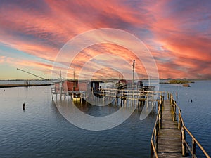 sunset at the pier in the Fishing hut with fishing net in the Comacchio lagoon in italy