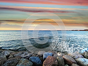 Seafront sunset colorful sky cloudy pink green water skyline, light reflection on seawater, gold summer