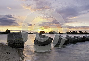 Sunset at Poole harbour with world war 2 tank traps in the foreground