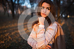 Sunset portrait of beautiful brunette young woman in autumn park