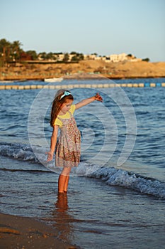 Sunset portrait of a happy dancing caucasian girl  in summer dress at the seashore