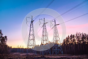 Sunset. Power line in late autumn on the background of forest glades in the rays of the setting sun, bright colorful beautiful sky