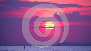 Sunset and purple cloud on sky over sea and surface little wave moving fishing boat passing