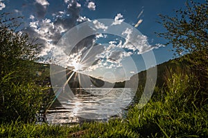 Sunset, a quiet reservoir in a valley, greenery and a forest in the area and everything is reflected in the water