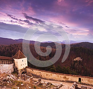 Sunset at Rasnov medieval citadel in Transylvania. Panoramic view of the defense wall and mountains in the horizon