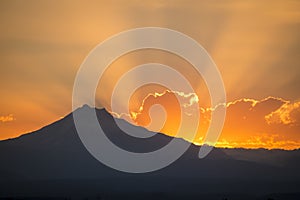 Sunset rays behind silhouette of mountain