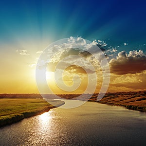 Sunset with rays in clouds over river