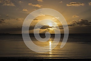 Sunset Rays over Calm Ocean with Rock Islands on Horizon