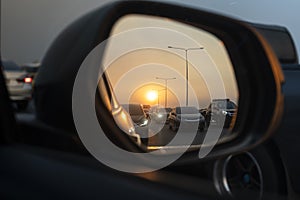 Sunset in a rear view mirror with traffic jams on expressways. sunset car driving scene