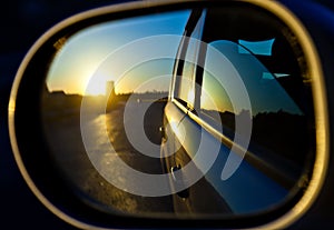 A sunset in the rearview mirror of car