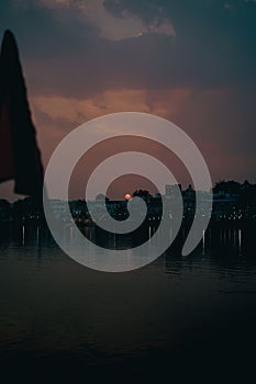 sunset reflected in water and clouds behind sailboats on lake