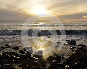 A sunset reflecting in the sea water with big waves in the front