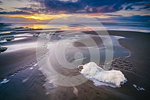 The sunset with the reflection of clouds in low tide water in Waddenzee, Texel, The Netherlands