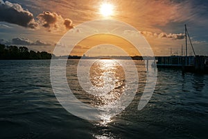 Sunset with reflections in the water in the port of the river Trave in Lubeck Travemunde at the Baltic sea, cloudy orange sky and