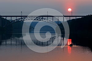 Sunset on the river, sun path and silhouette of people in a boat. railway bridge over the river in summer