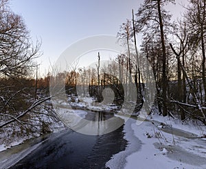 sunset on a river whose banks are covered with ice