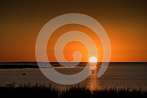 Sunset rocky beach, peaceful sea, orange sky. Kihnu, small island in Estonia.