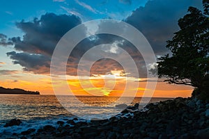 Sunset on a rocky coastal beach with orange and blue clouds