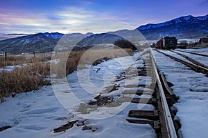 Sunset in the Rocky Mountains with train tracks in the snow