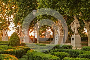 Sunset by Royal Palace or Palacio Real with Plaza de Oriente park statues and sun flares through the trees, Madrid Spain