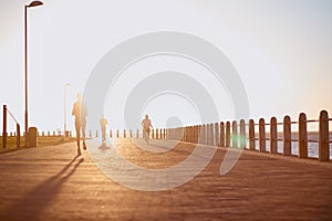 Sunset runners. A young woman exercising outdoors with other people in the background.