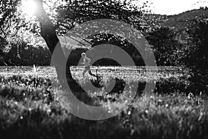 Sunset and running young man on spring meadow. Black and white photo