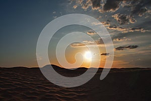 Sunset in the Sahara desert over the peaks of sand dunes