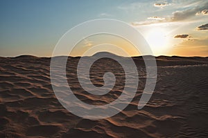 Sunset in the Sahara desert over the peaks of sand dunes