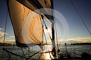 Sunset at the Sailboat deck while cruising sailing at opened sea or river. Yacht with full sails up at the end of windy