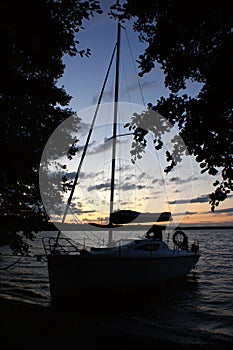 Sunset sailing yacht sailboat moored on a dead lake